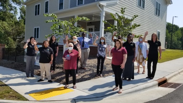 TROSA women's program staff and residents wave in front of award-winning homes