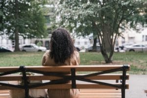 A woman sits on a bench with her back facing us