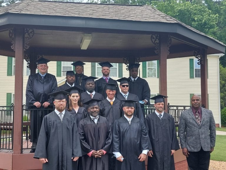 TROSA Spring 2022 Graduates with Pierre Bynum standing outside on TROSA's grounds under a gazebo