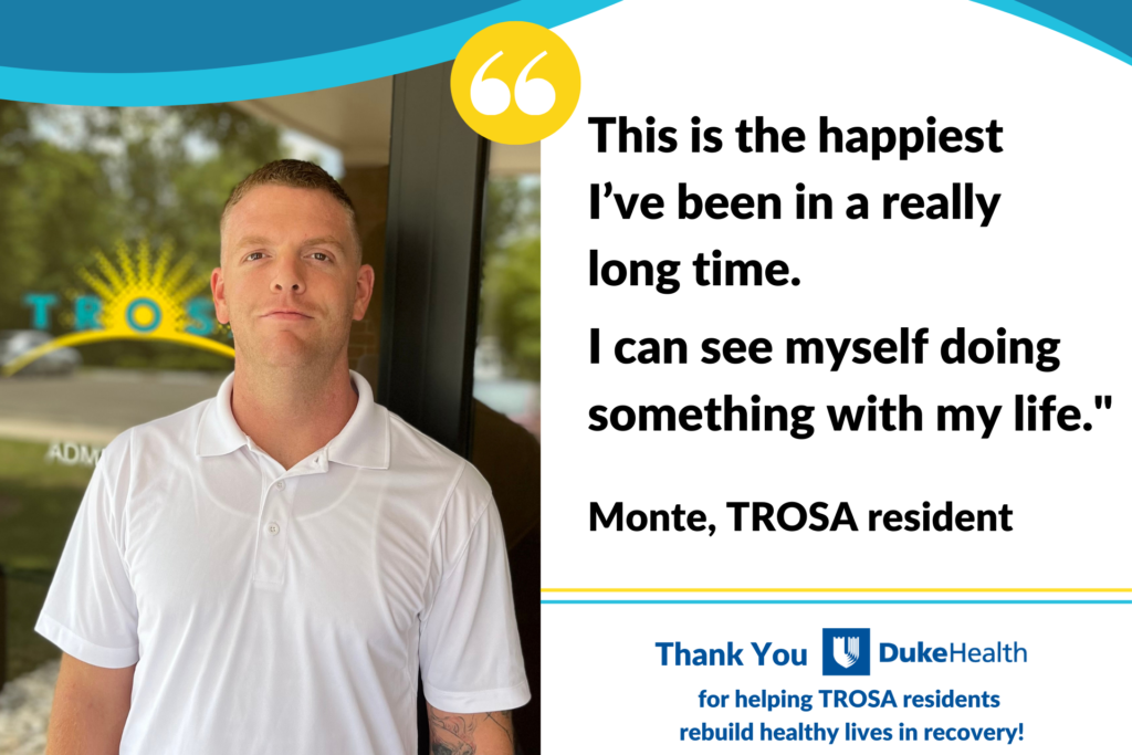 Photo of TROSA resident Monte who has stopped smoking while at TROSA. Monte is standing in front of the TROSA campus administration doors.