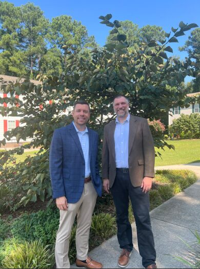 (from L to R): Truist Triangle West Market President Jordan Clark and TROSA President and CEO Keith Artin at TROSA's campus, standing in front of a tree and flowers